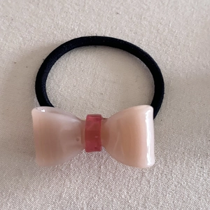 Elegant jelly-colored acetate bow hair tie with pink resin finish and black elastic band