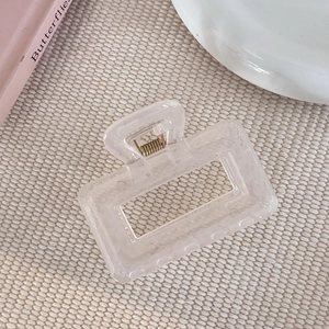 Détail d'une pince à cheveux rectangulaire crème givrée avec un ressort en métal doré robuste