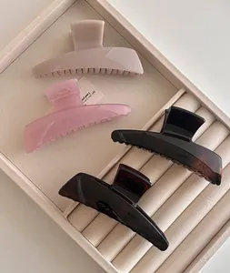 Macro view of four large acrylic hair claws in coffee and cream tones on a velvet tray