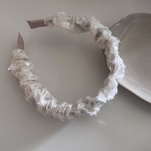 Macro detail of white sequined fabric headband with ruched texture and shimmering accents