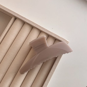 Elegant large trapezoid acrylic hair claw clip in matte dusty rose on beige velvet base
