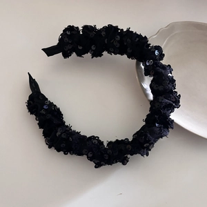 Detailed view of the black sequined headband with ruffled texture and retro design