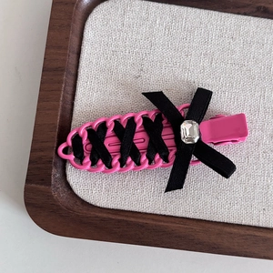 Detailed view of ballet style pink hair clip with black ribbon bow and square crystal