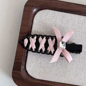Detail of pink ribbon weave on black duckbill hair clip with crystal bow accent