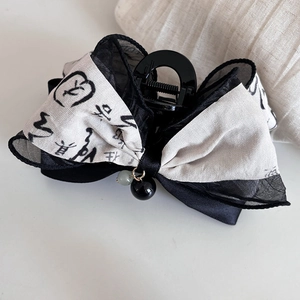 Detail of a Chinese ink style bow hair claw with elegant calligraphy and hanging beads