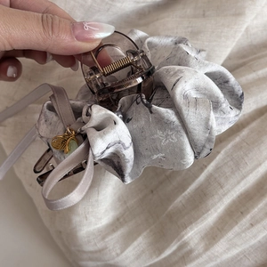 Detail of a large hair claw clip with ink-style fabric and a gold Fu character pendant