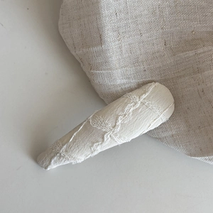 Détail de la pince à cheveux en jacquard avec dentelle florale et perle sur lin blanc