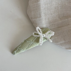 Gros plan sur la barrette en tissu jacquard avec un nœud en perles vert clair