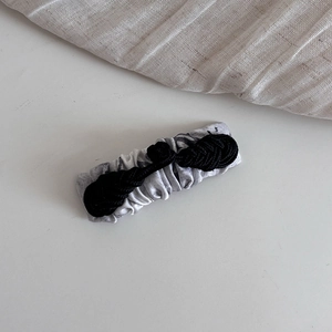 Detail of grey marble silk hair clip featuring a black Chinese frog button knot