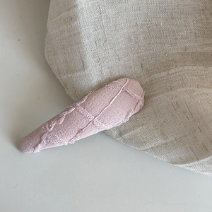 Gros plan sur la barrette goutte en tissu rose avec dentelle délicate et texture florale