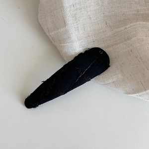 Gros plan sur la texture du tissu jacquard noir d'une pince à cheveux BB en métal