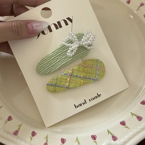 Plaid and ribbed fabric hair clip set with pearl bow on decorative floral ceramic plate