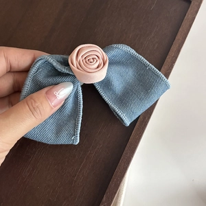 Vue détaillée d'une pince à cheveux en denim avec une petite rose en satin rose
