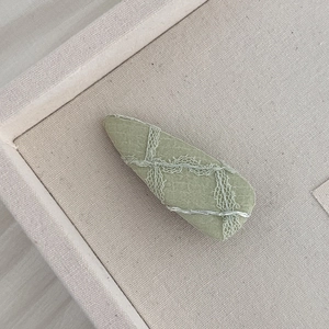 Gros plan sur la barrette en tissu vert clair avec dentelle et texture tissée