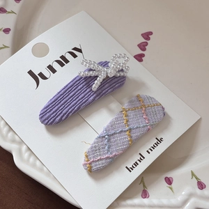 Detail view of handmade purple plaid hair clips with pearls on a decorative card