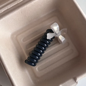 Detail of navy blue spiral hair tie with a white pearl-texture handmade bow decoration