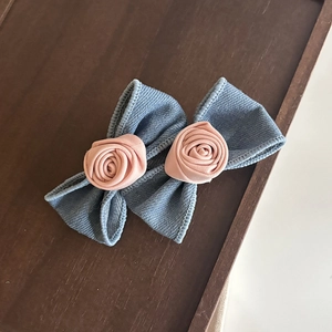 Barrette à cheveux en denim bleu avec roses en satin rose sur un plateau en bois