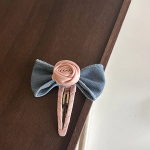 Détail de nœud en ruban bleu et rose en satin sur une pince à cheveux rose