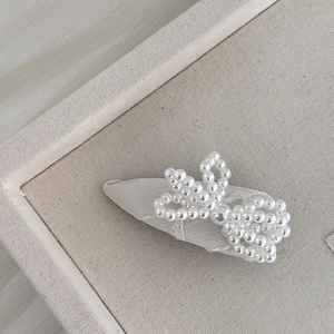 Détail d'une barrette nœud en perles avec base en dentelle blanche pour accessoire de coiffure