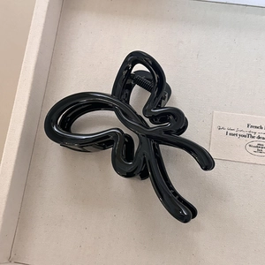 Gros plan d'une pince à cheveux papillon noire brillante en résine de qualité