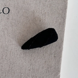 Vue détaillée du tissu noir texturé recouvrant la barrette à cheveux BB triangulaire