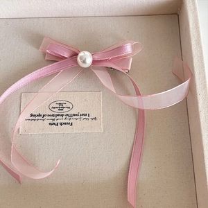 Dettaglio di fermaglio per capelli con fiocco in pizzo rosa, organza e perla
