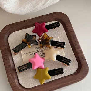 Set of six star-shaped acetate hair clips in assorted colors on a linen background