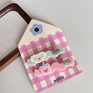 Detail of cute bear and dog cartoon hair clips on a purple checkered card packaging