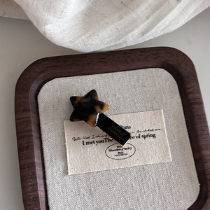 Detail of star-shaped acetate hair clip with tortoiseshell pattern and handmade text