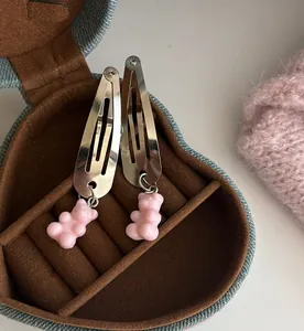 Detailopname van roze harsbeertjes hangers op zilveren metalen klikhaarspelden voor haar