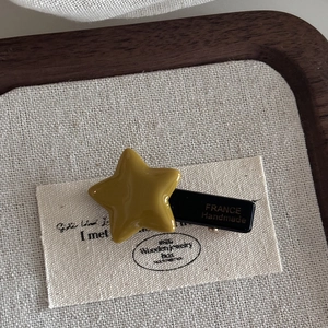 Detail of star-shaped acetate hair clip in mustard yellow with France Handmade mark