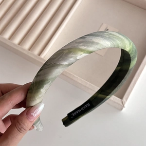 Detail of handmade thick green marbled headband showing refined fabric texture and woven label