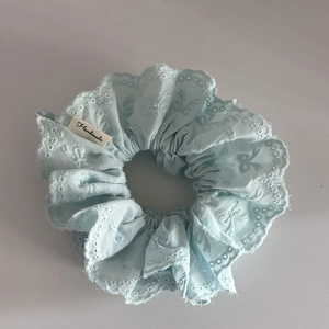 Detail of light blue lace scrunchie with floral embroidery and handmade fabric label