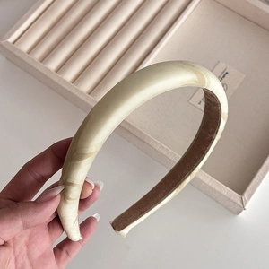 Close-up of a thick beige satin headband with silk texture and non-slip inner lining