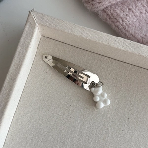 Zilveren haarclip met witte beer hanger op een elegante crème stoffen dienblad