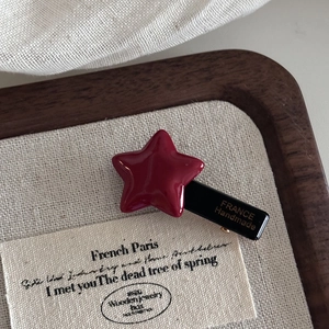 Close-up of red star hair clip with France Handmade lettering on a beige linen tray