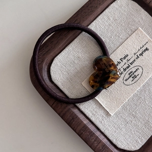 Détail du pendentif cœur en acétate léopard avec gravure artisanale sur élastique marron