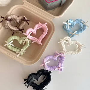 Dettaglio di 7 mollette a cuore colorate con rivestimento in stoffa e fiocchi