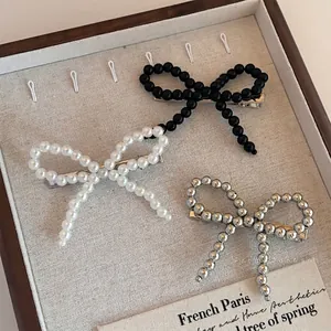 Three-piece set of beaded bow hair clips in pearl white, matte black, and metallic silver