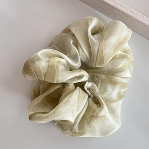 Champagne satin hair scrunchie with brown tiger print on a clean white desk surface
