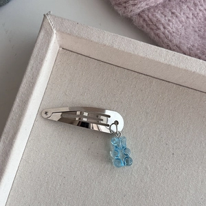 Detailopname van een zilveren haarklem met een lichtblauwe doorschijnende beertjeshanger