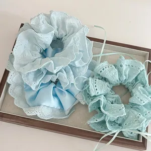 Vue détaillée de chouchous en dentelle bleu bébé et vert menthe sur un plateau en bois