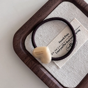 Détail du charm cœur crème avec texte France Handmade sur un élastique marron