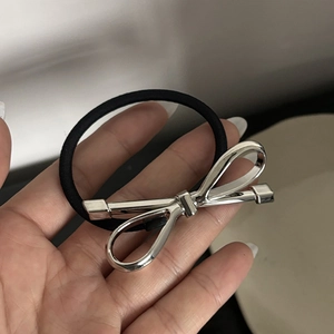 Silbernes Schleifen-Metallhaargummi mit schwarzem Gummiband in der Hand für die Frisur