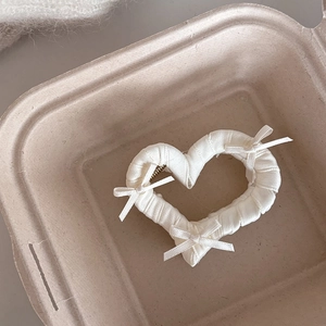 Dettaglio di un mollettone a cuore con fiocchi di nastro bianco e tessuto a pieghe