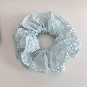 Détail du chouchou en dentelle bleu clair avec broderie anglaise et bords ondulés