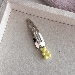 Detail van een zilveren haarclip met een schattige gele gummybeer hanger op canvas textuur