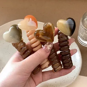 Set of four earth-toned heart charm spiral hair ties in brown and beige shades