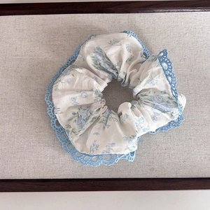 Détail du chouchou floral avec bordure en dentelle bleue et texture de coton doux