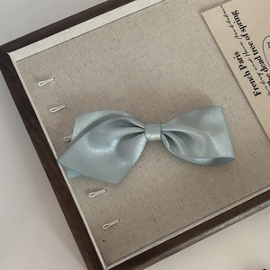 Elegant asymmetrical light blue satin bow hair clip with pearlescent finish for women
